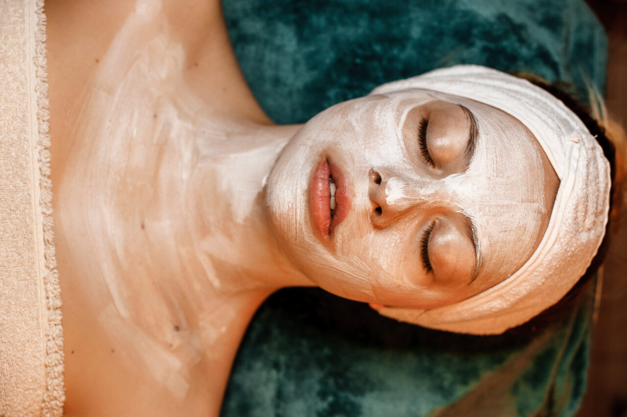 Upper view of a charming young woman resting with eyes closed with a mask on her face and body in a spa center.