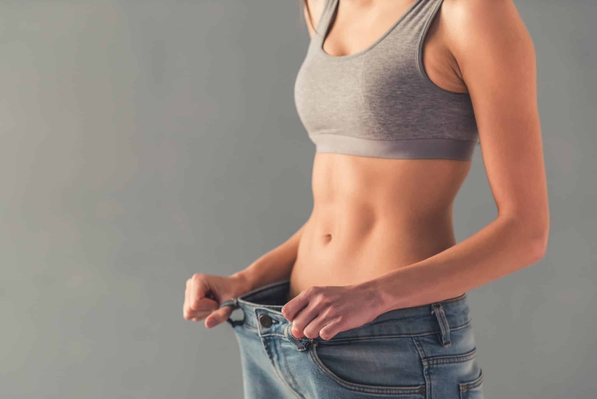 Cropped image of girl pulling her big jeans and showing weight loss